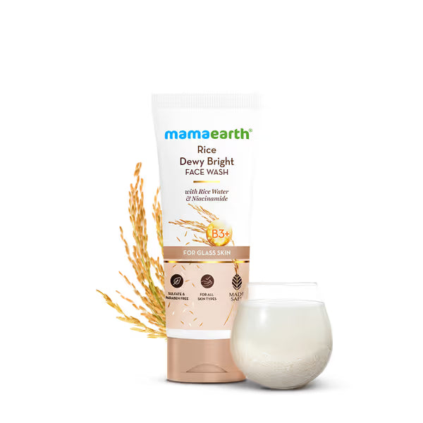 Mamaearth Rice Dewy Bright Face Wash with rice grains and a glass of water on a white background