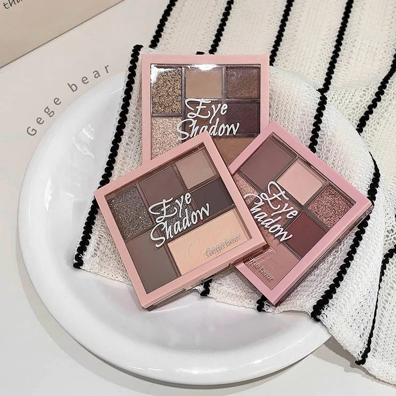 Three eye shadow palettes on a white plate with a striped towel underneath.