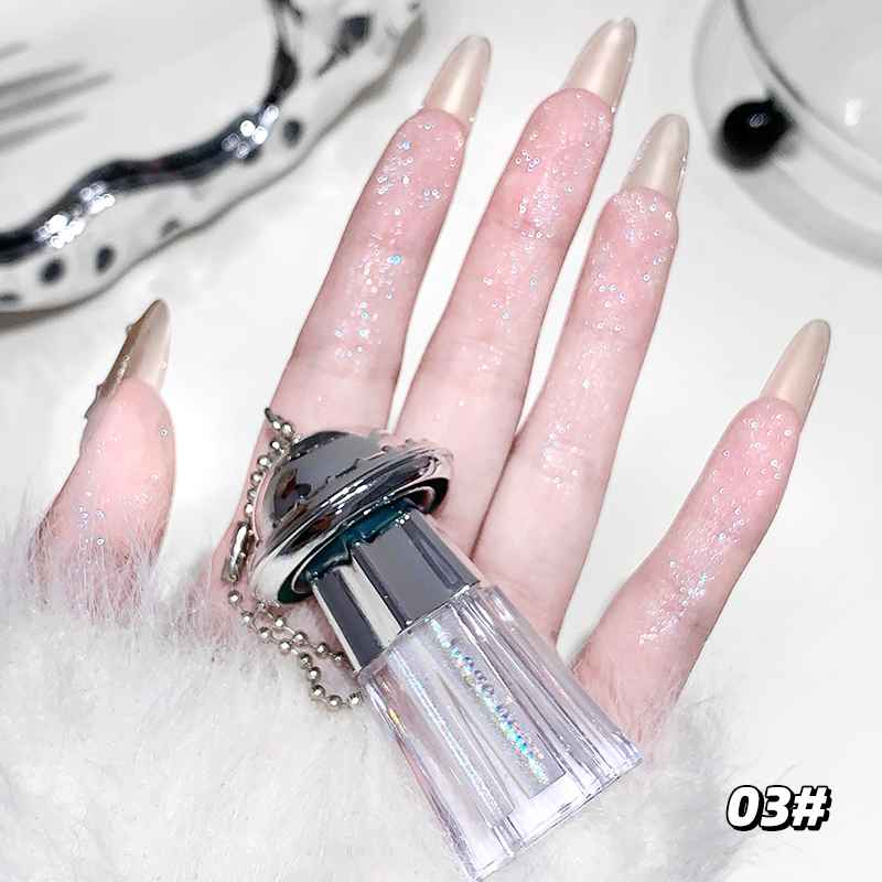 Hand with long, glittery nails holding a clear Eyeshadow Palette bottle with a silver cap.