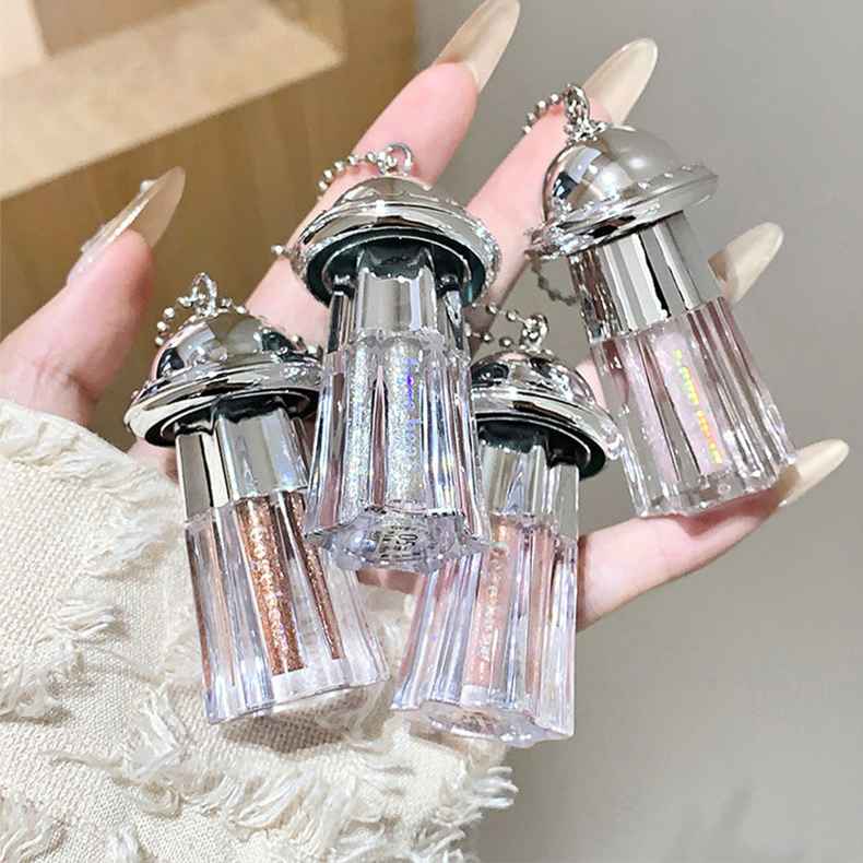 Hand holding multiple small, decorative Eyeshadow Palette bottles with glittery contents against a neutral background