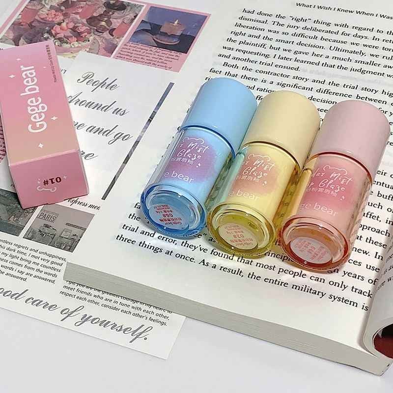Four lip glosses in different colors on an open book