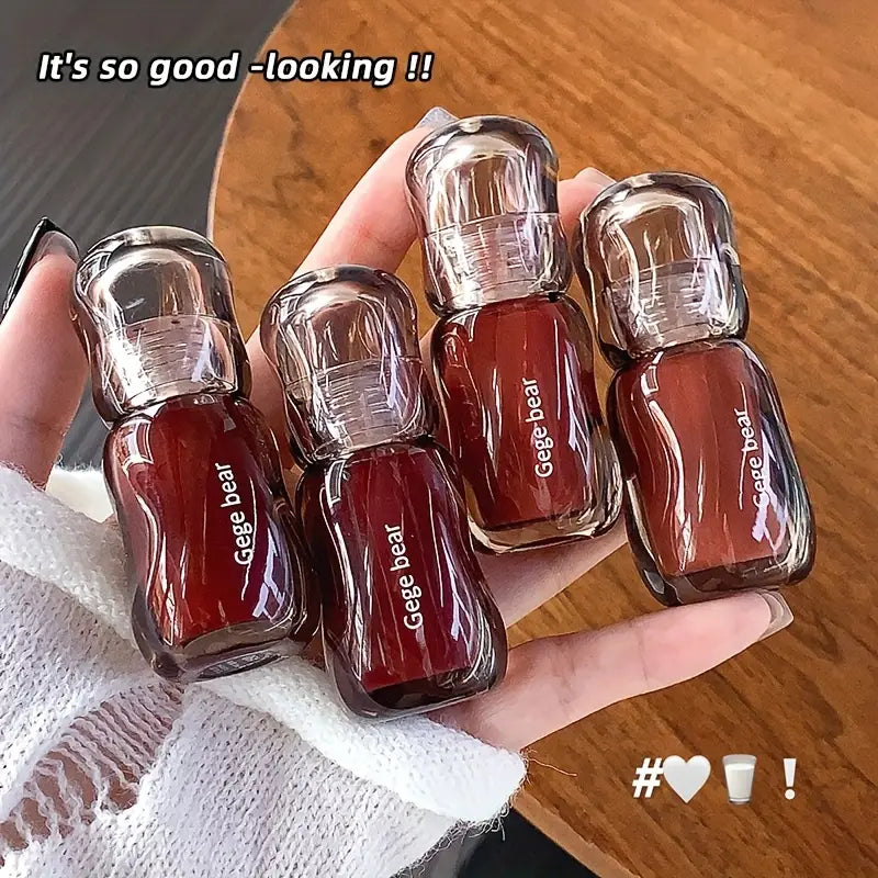 Hand holding four small Gege Bear nail gloss bottles with a wooden surface in the background.