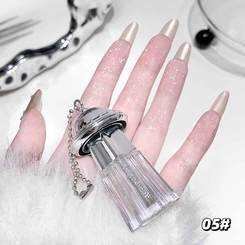 Hand with long, glittery Eyeshadow Palette holding a clear bottle with a silver cap.