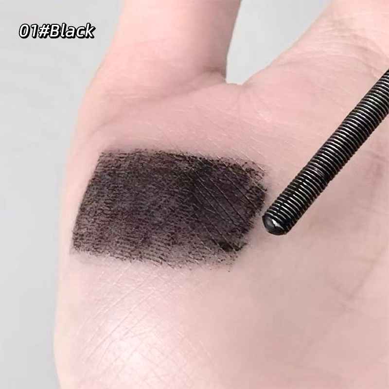 Black mascara swatch on a person's eyelid with a black eyeliner pencil next to it.