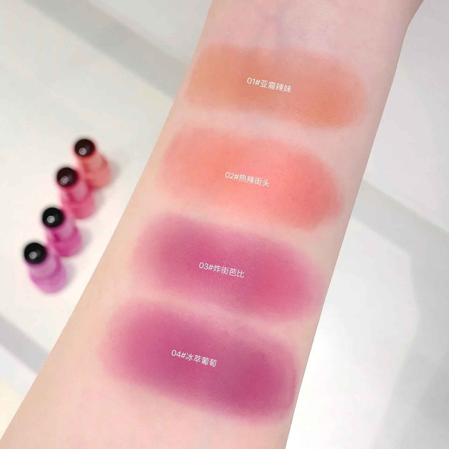 Blush stick swatches on a person's arm with four different shades.
