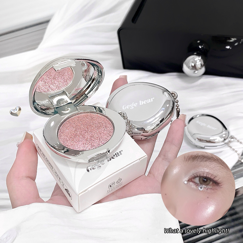 Blush with pink glittery shade held by a hand, with a blurred background.