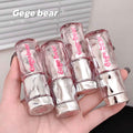 Clear lip gloss tubes with pink text held in a hand, branded 'Gege bear'.