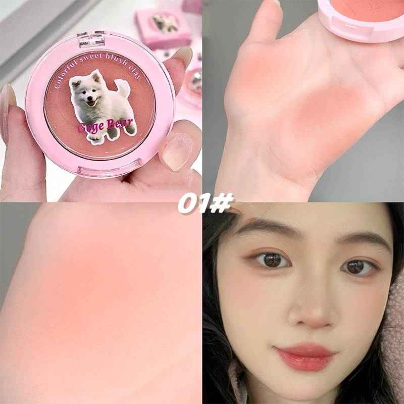 Compact blush with a dog illustration on the cover, applied to skin, and worn by a person.