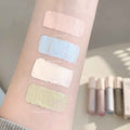 Concealer swatches on a person's arm with product bottles in the background