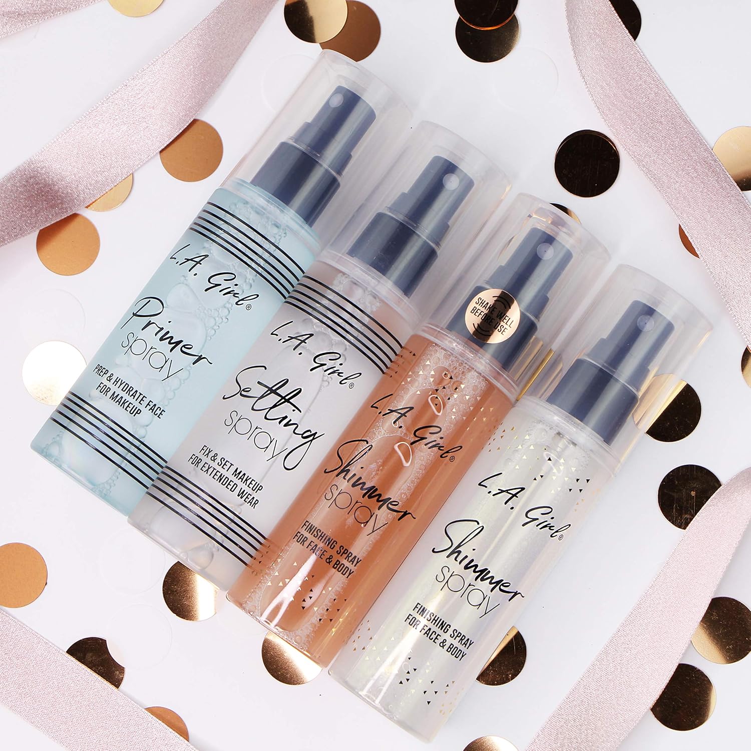 Four L.A. Girl spray bottles on a polka dot background