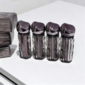 Four black and silver skincare devices on a white surface with a box in the background.