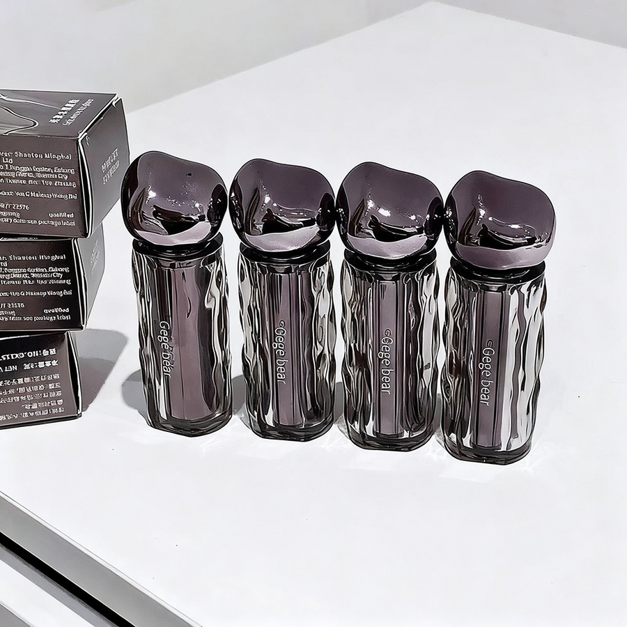 Four black and silver skincare devices on a white surface with a box in the background.