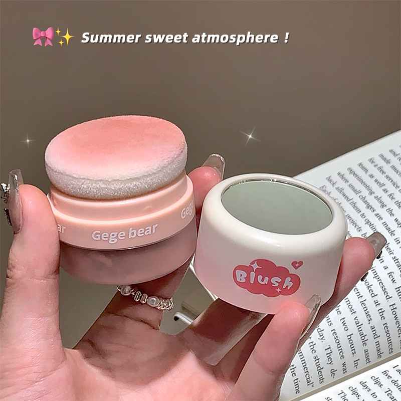 Two small cosmetic containers labeled 'Gege bear' and 'Blush' held by a hand against a blurred background.