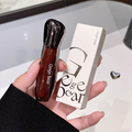 Hand holding a Gege Bear lip gloss and its packaging against a neutral background