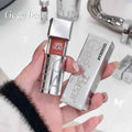 Hand holding a silver lip gloss with 'Gege Bear' branding against a blurred bathroom background.