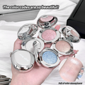 Hand holding open blush with glittery shades on a white surface