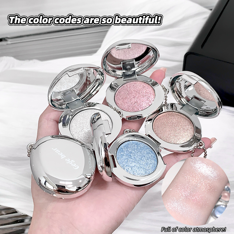 Hand holding open blush with glittery shades on a white surface