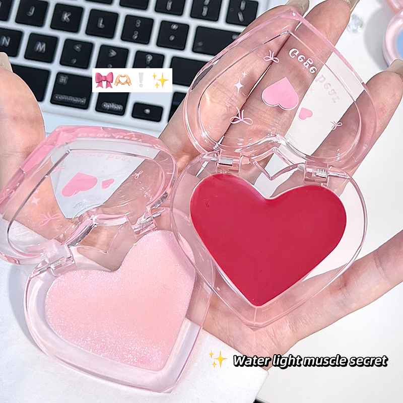 Heart-shaped blush compact held by hands with a laptop in the background