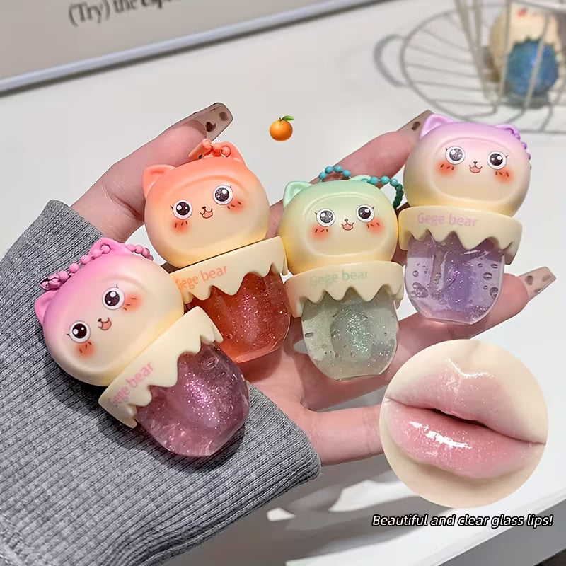 Clear lip oil in a sleek tube shown with a glossy applicator, reflecting a soft, luminous shine. The product appears lightweight and moisturizing, suggesting smooth, hydrated lips with a natural, non-sticky finish.