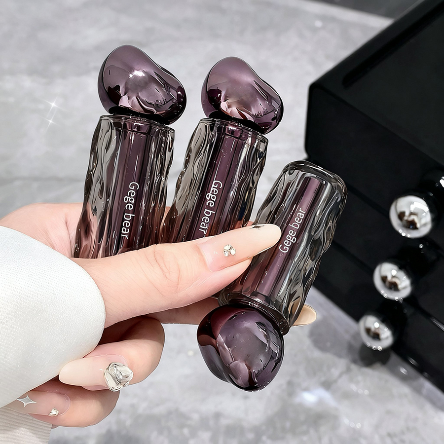 Hand holding three purple heart-shaped bottles with 'Gege bear' branding on a reflective surface.