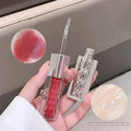 Lip gloss with a clear case held in a hand, showing a close-up of the product.