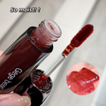 Lip gloss with applicator and close-up of color on a white background
