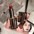 Lipstick with open case held by a hand, brand 'Cage Bear' visible
