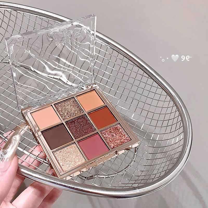 Makeup palette with various shades held by a hand on a metal chair.