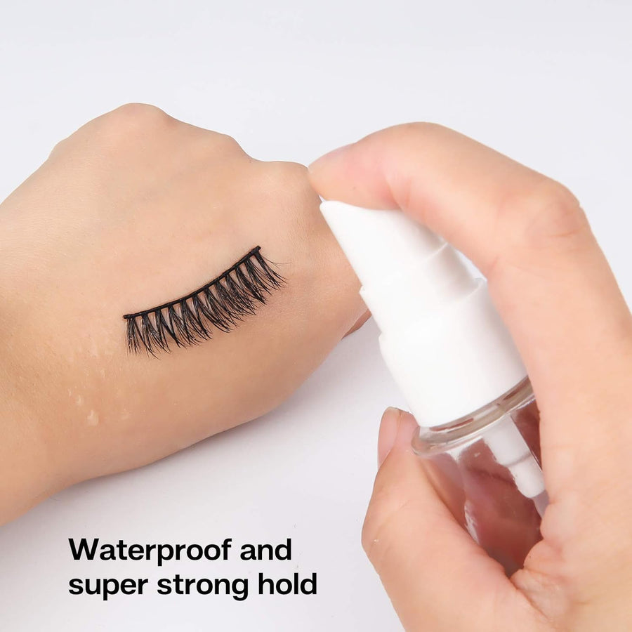 Person applying eyelash adhesive to false eyelashes with a small bottle on a white background.
