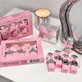 Pink 'Gege Bear' product packaging and items on a white surface with a candle and mirror.