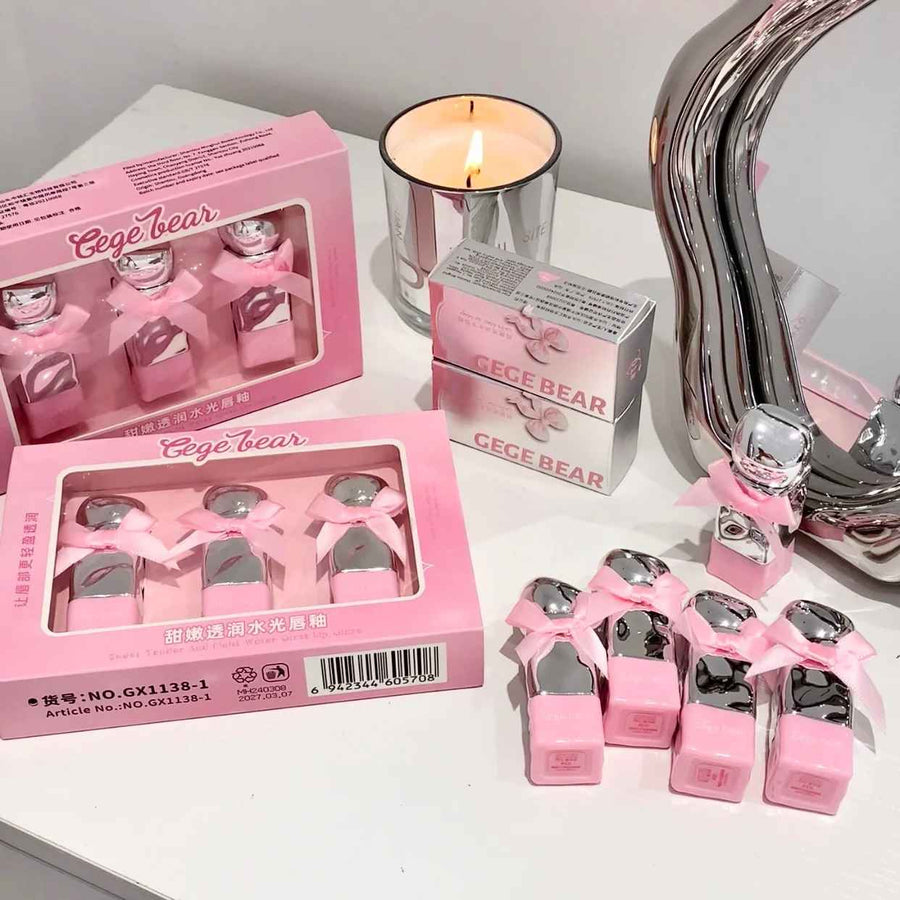Pink 'Gege Bear' product packaging and items on a white surface with a candle and mirror.