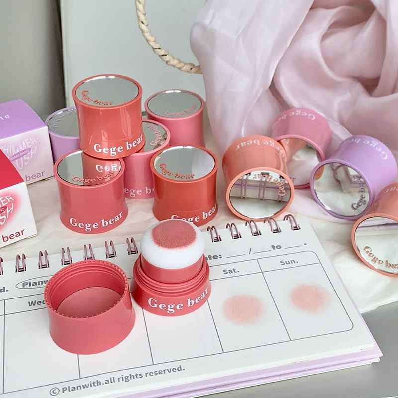 Pink and red blush containers with 'Gege bear' branding on a planner.