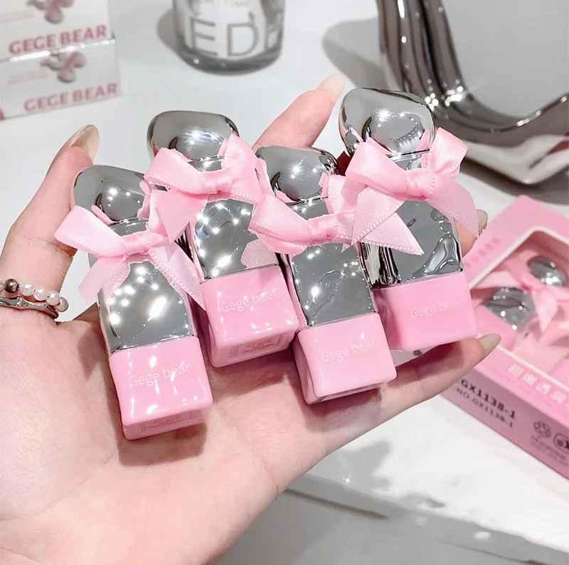 Pink and silver heart-shaped boxes of lipsticks with bows held in a hand, with 'GEGEBEAR' branding in the background.
