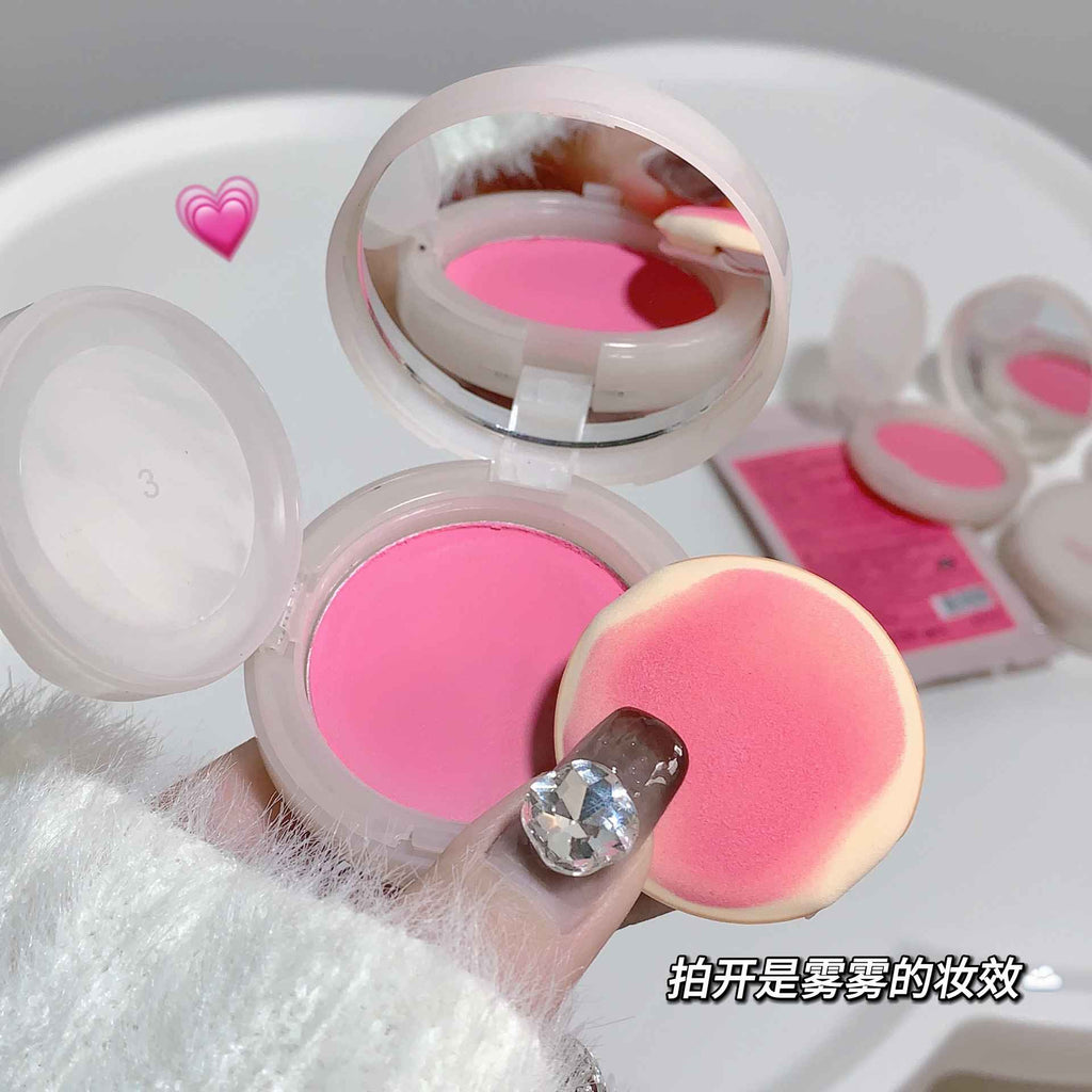 Pink blush and a sponge applicator on a white background