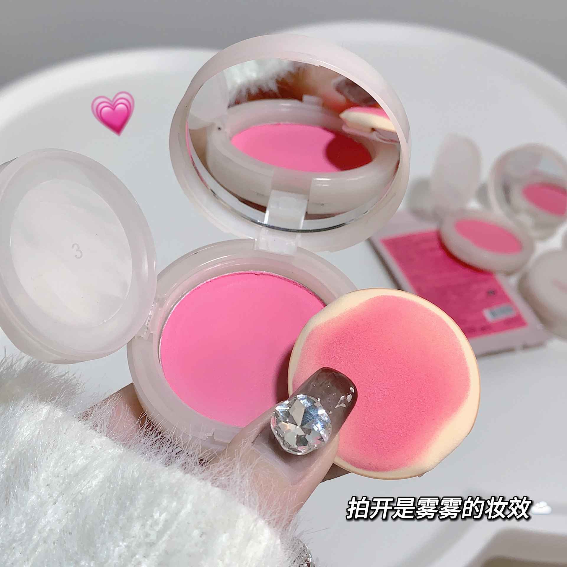 Pink blush and a sponge applicator on a white background