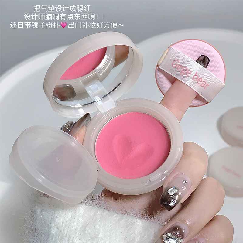 Pink blush and heart design held by a hand.