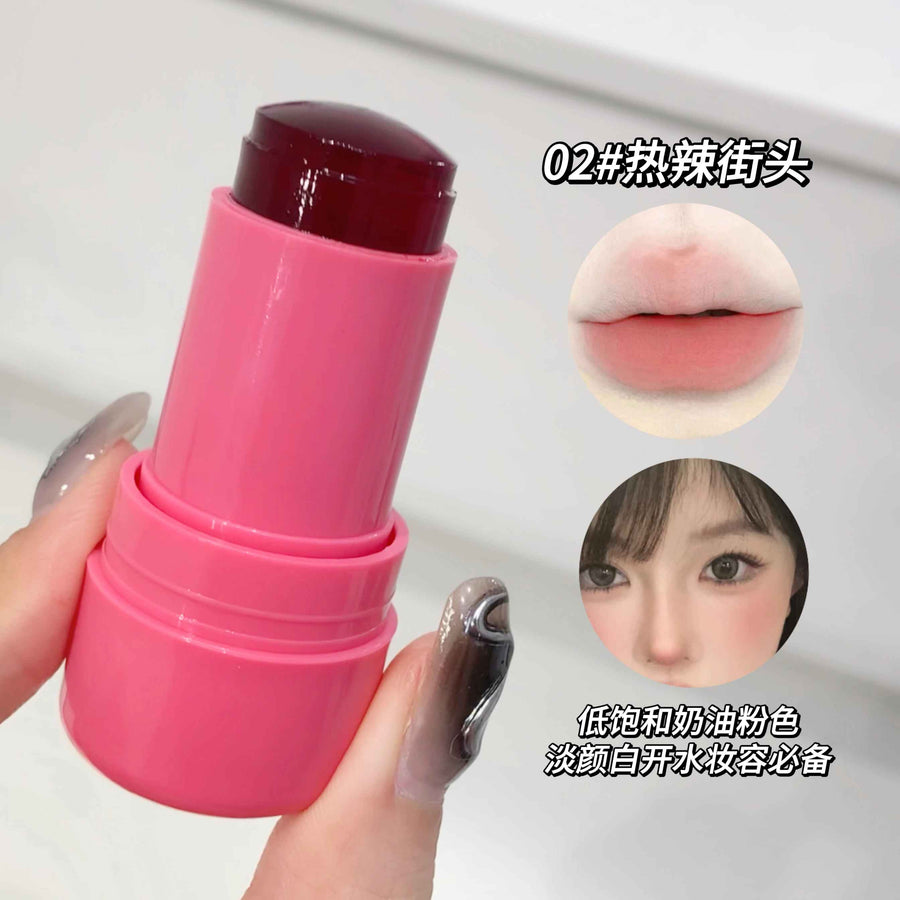 Pink blush stick held by a hand with a close-up of a lip color swatch and a person's face.