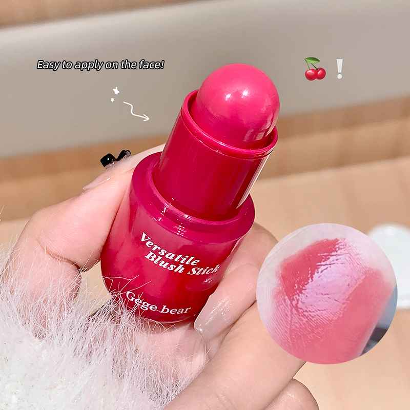 Pink blush stick held by a hand with a blurred background