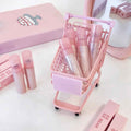 Pink cosmetic products and trolley on a white background
