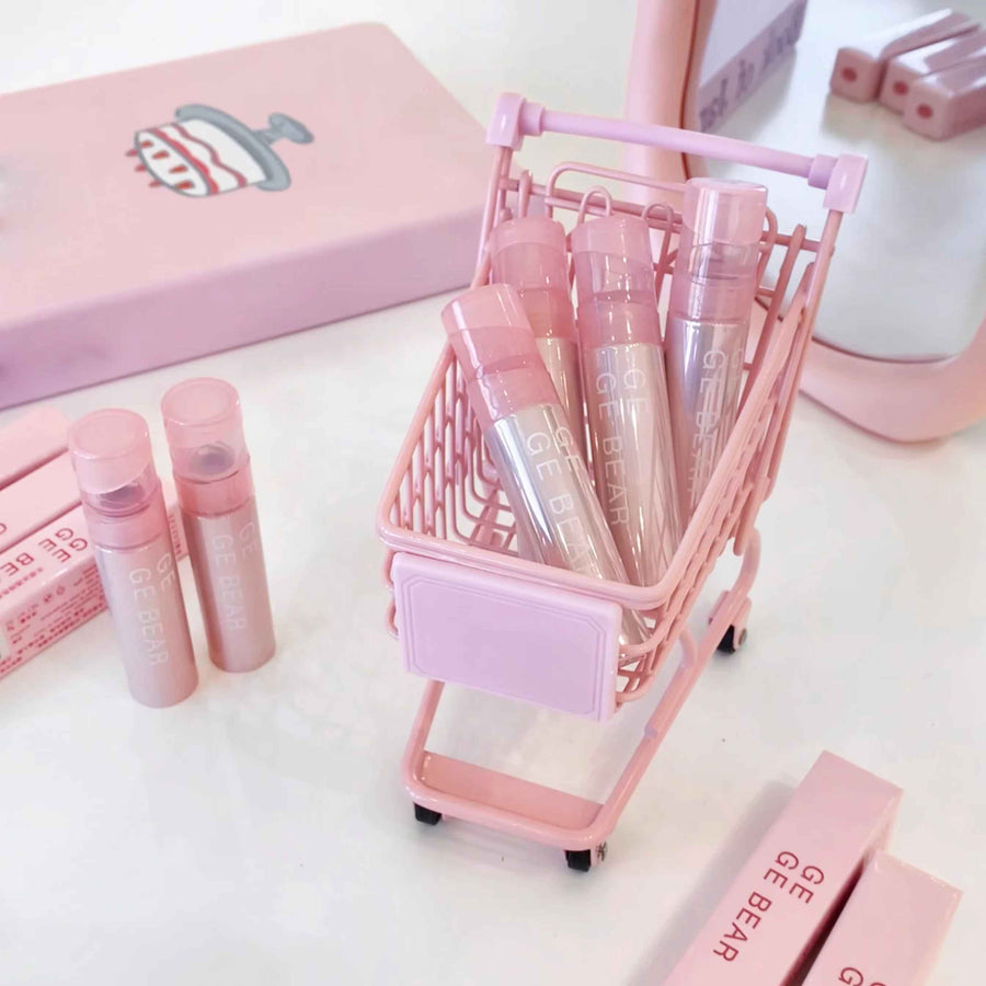 Pink cosmetic products and trolley on a white background