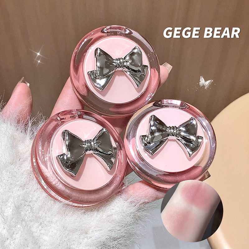 Pink lip balm with silver bows held by a hand against a neutral background, featuring the brand 'GEGE BEAR'.