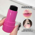 Pink lip balm with black cap held by a hand, close-up on a white background.