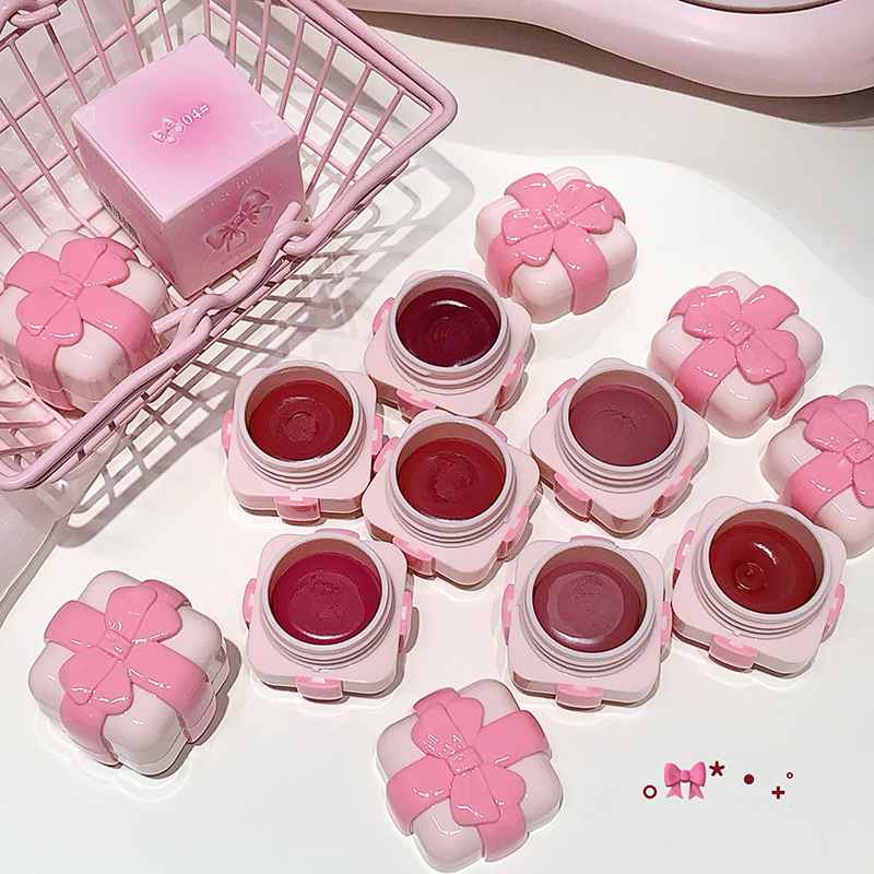 Pink lip balm containers with floral designs on a white surface.
