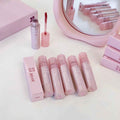 Pink lip gloss set with packaging on a white surface