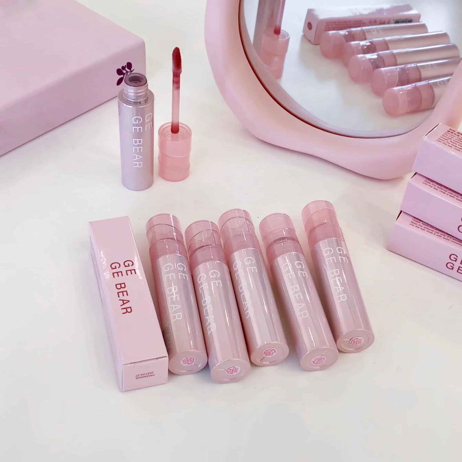Pink lip gloss set with packaging on a white surface