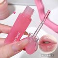 Pink lip gloss with applicator held by a hand, close-up on a white background.