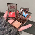 Three gege bear blushes palette with butterfly designs on the lids, held in a hand brand by gege bear 