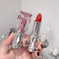 Red lipstick held by a hand with a blurred background