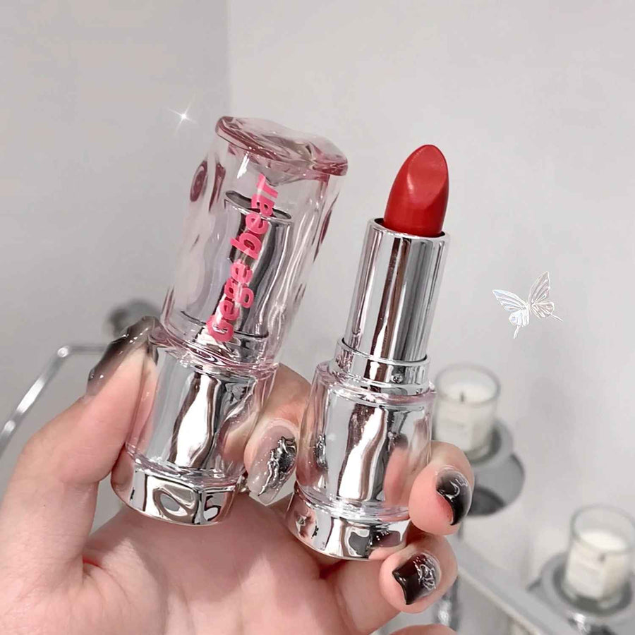 Red lipstick held by a hand with a blurred background