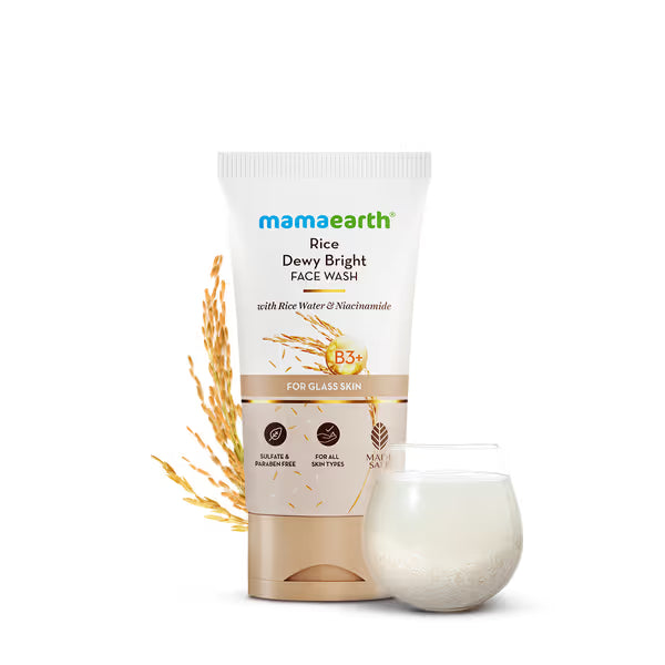 Mamaearth Rice Dewy Bright Face Wash with rice grains and a glass of water on a white background